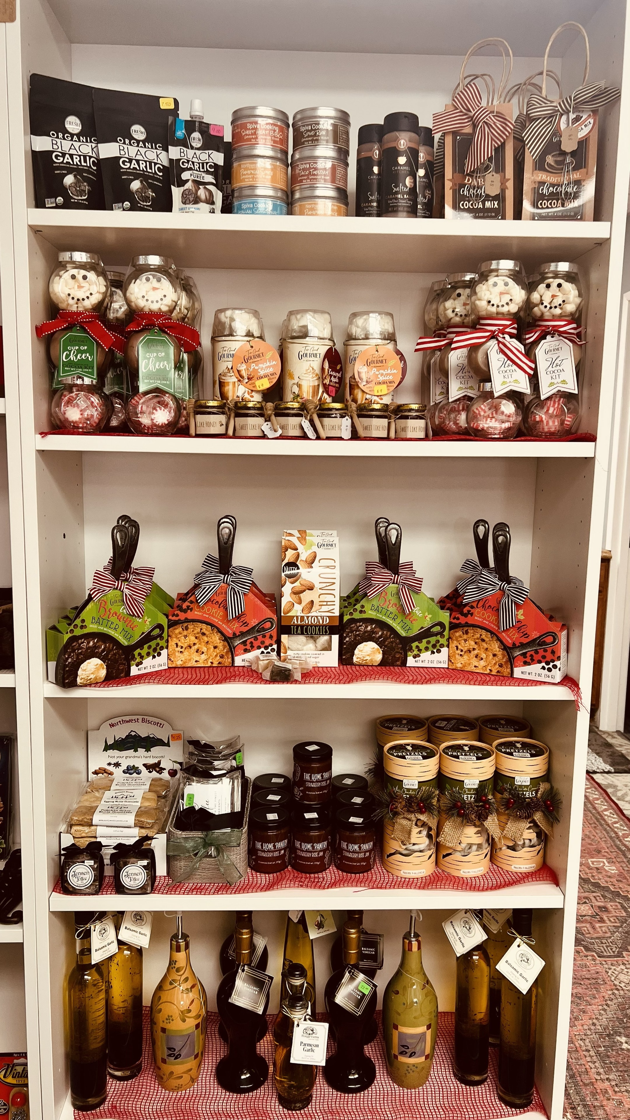 Gourmet pantry shelf with artisan oils, cocoa mixes, baking kits, biscotti, and holiday food gifts