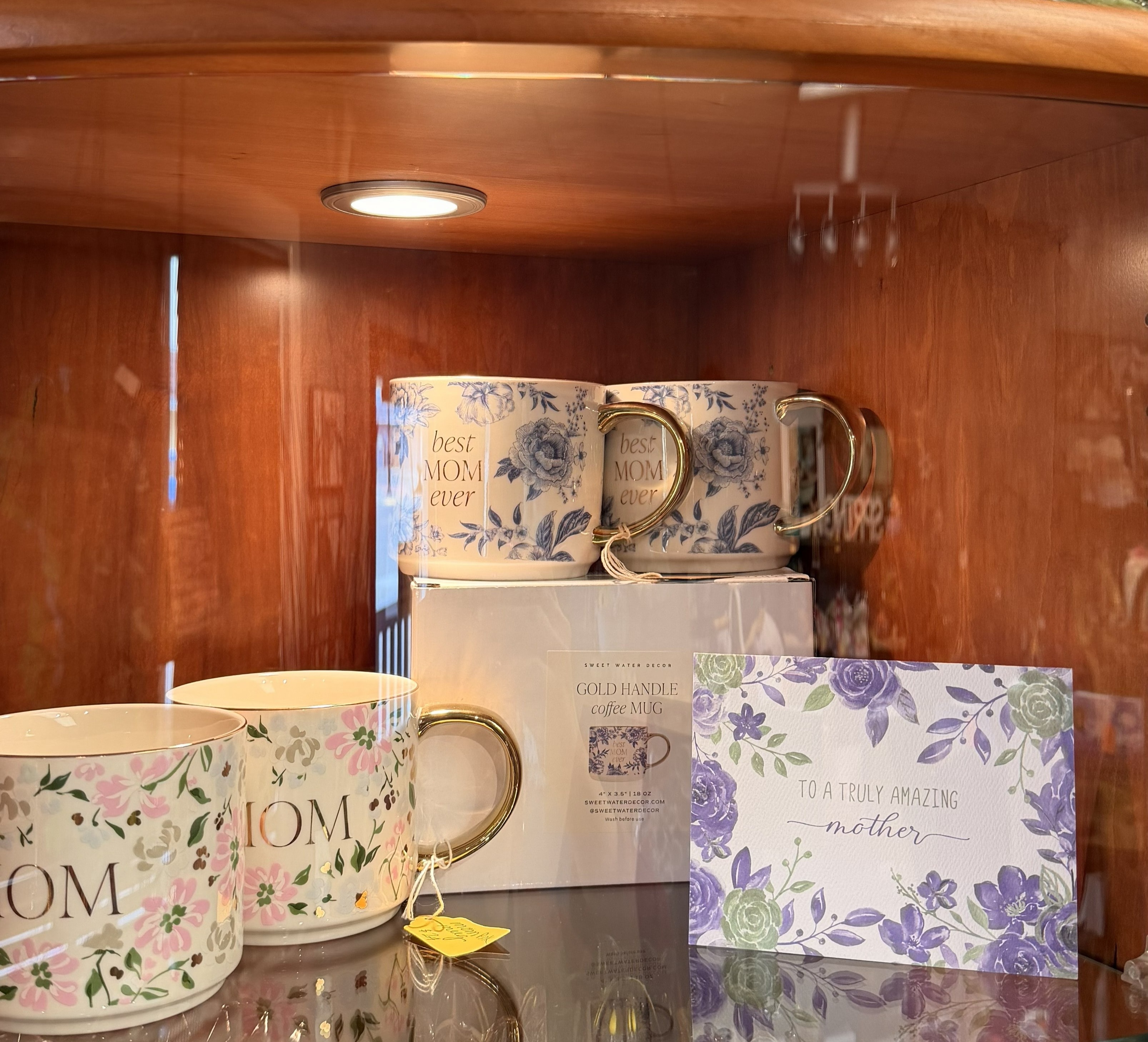 Gifts for her including floral gold-handle mugs, Best Mom Ever mugs, and a Mother's Day card