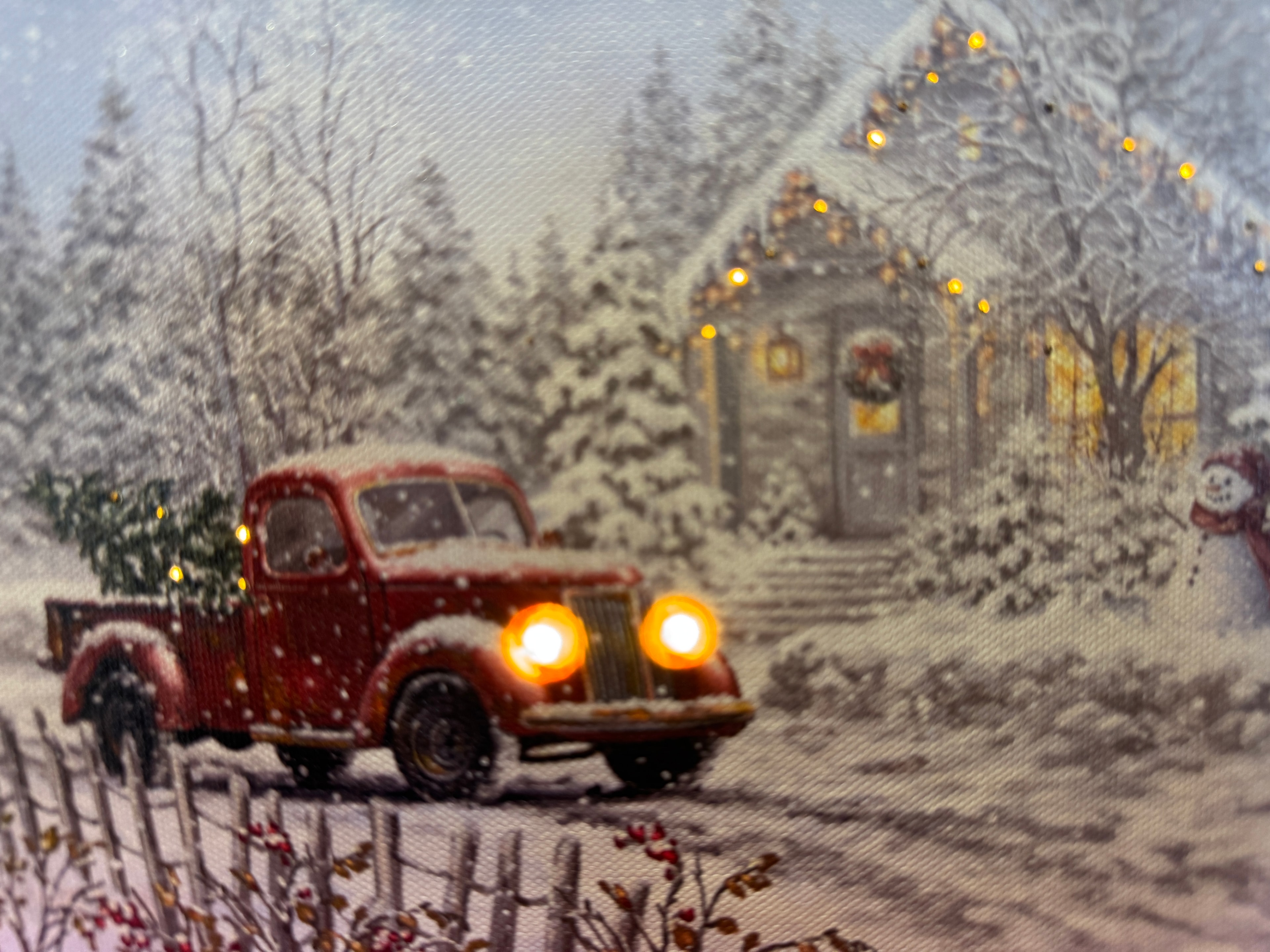 Lit canvas art print of a red vintage truck carrying a Christmas tree through a snowy scene with a glowing cabin