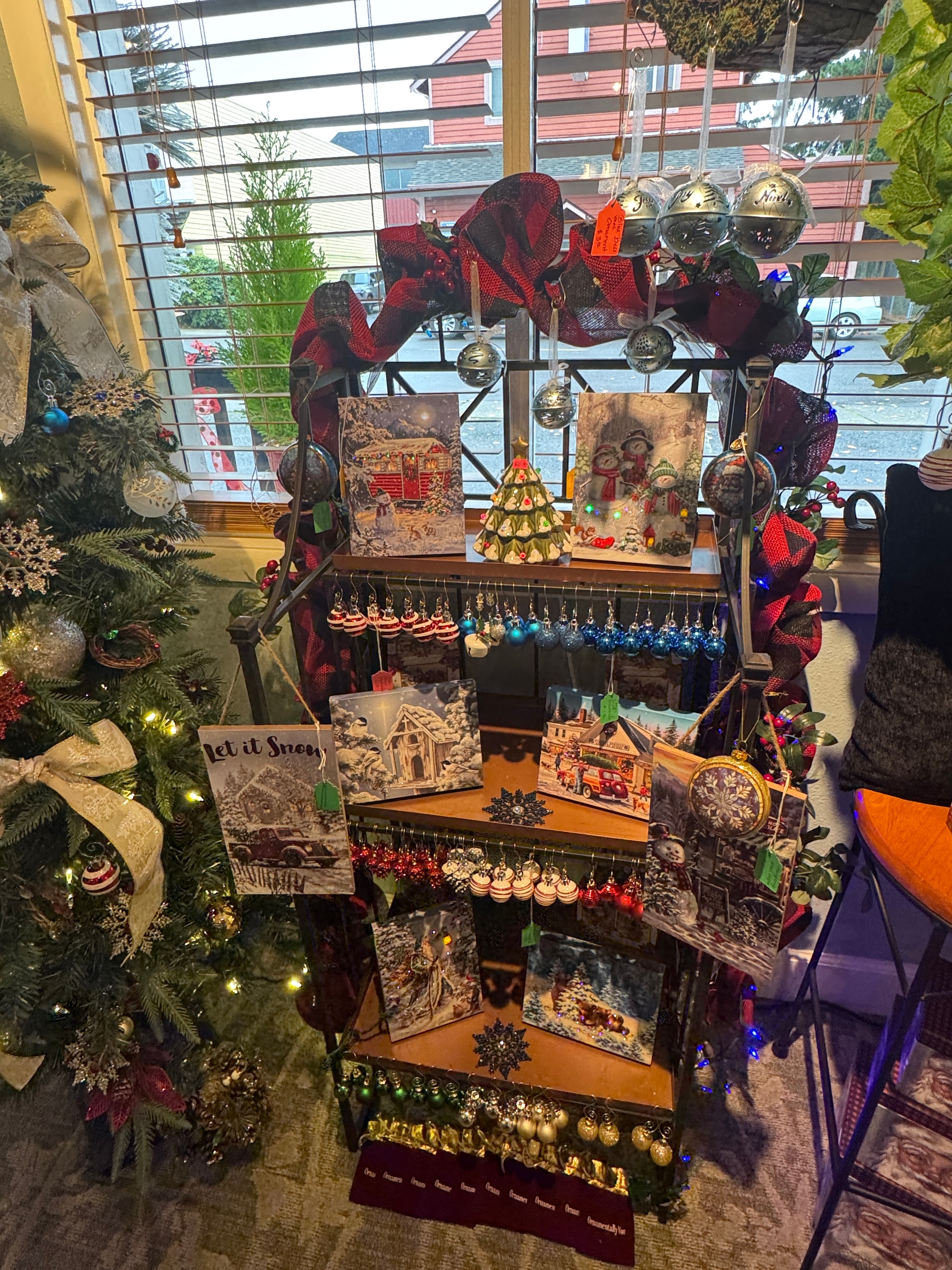 Christmas display with wrought iron reindeer figurines, glowing candles, greeting card rack, and holiday ornaments