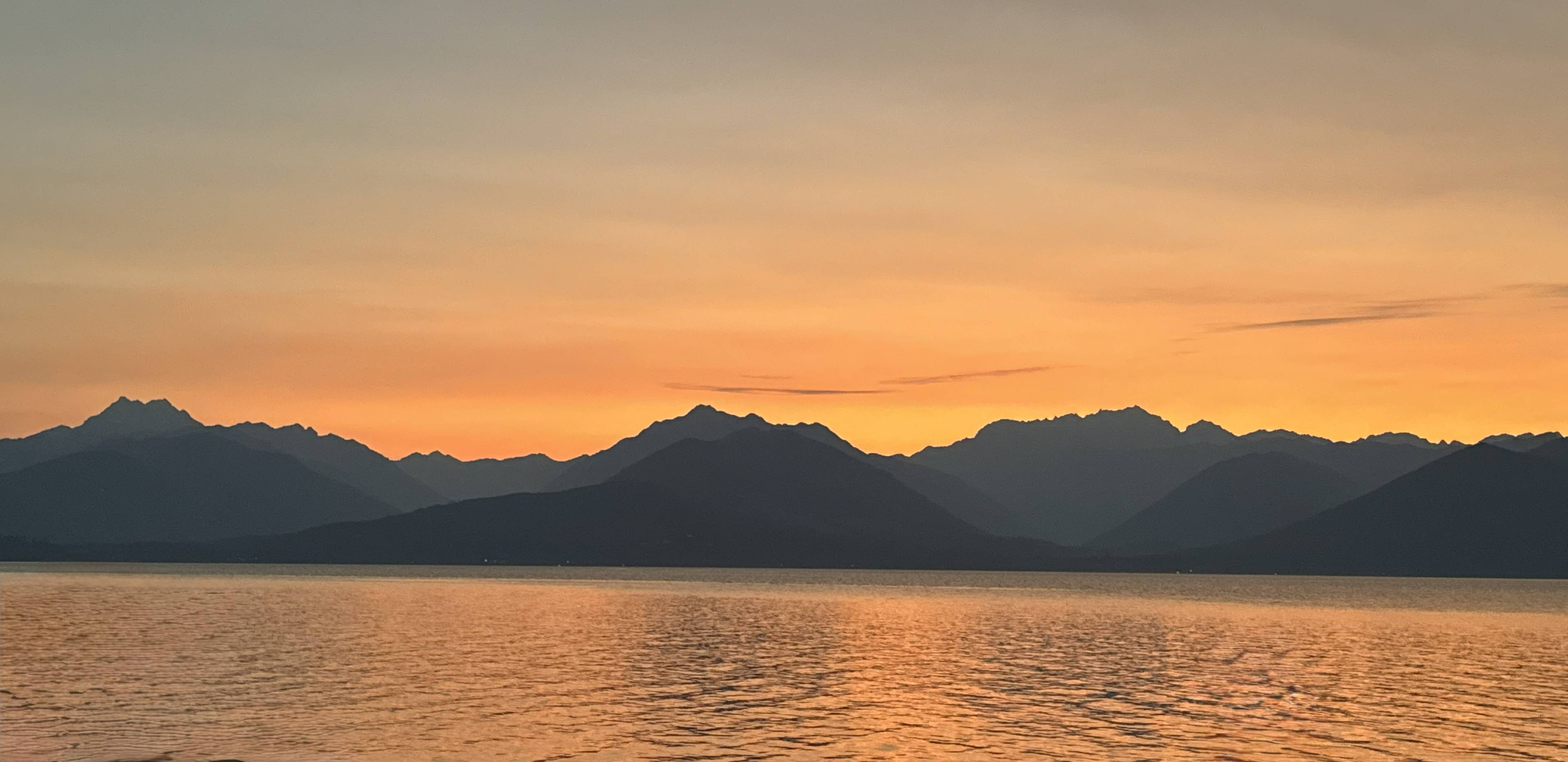 Sunset view of the Olympic Mountains across calm water